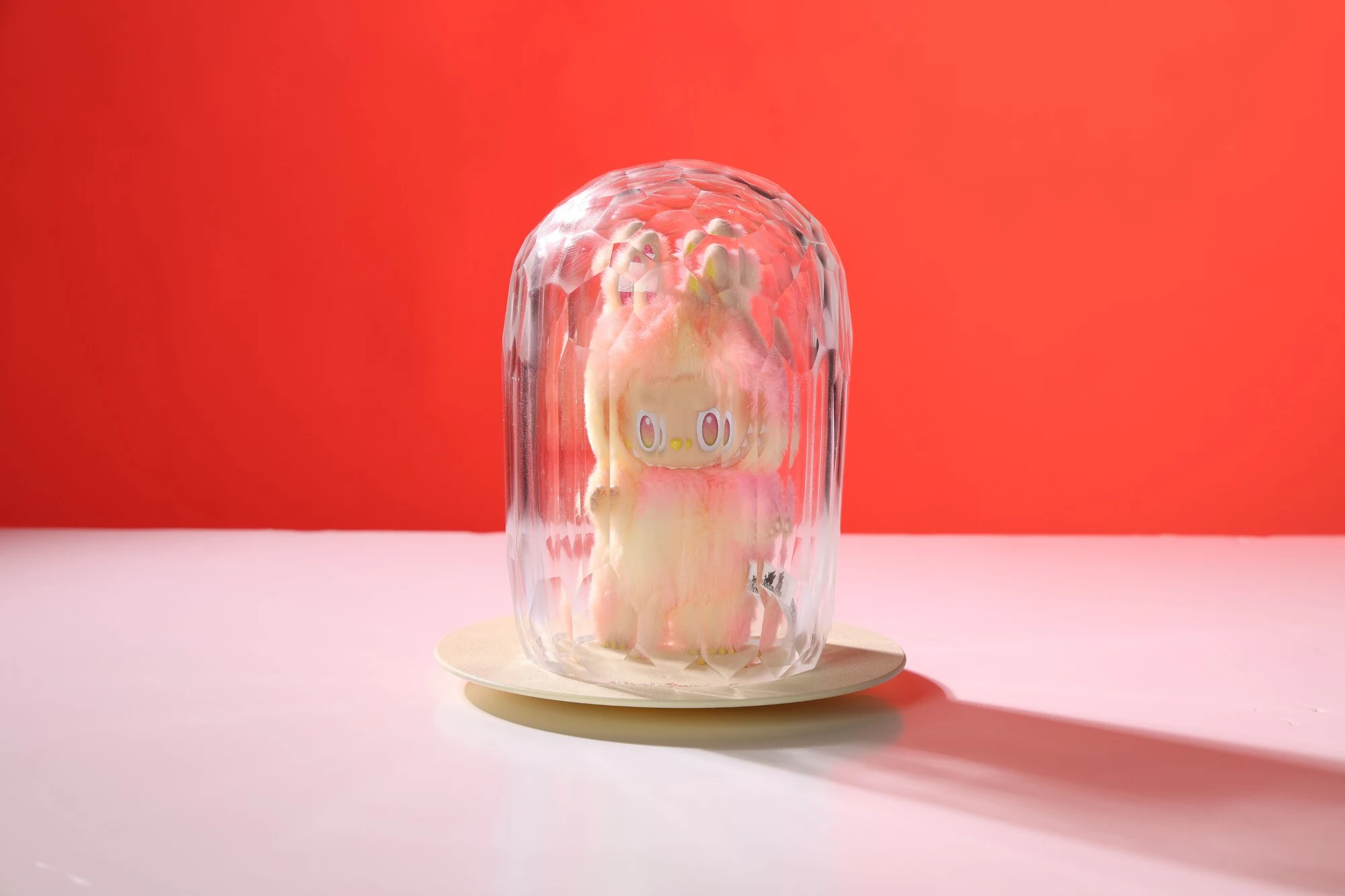 The same piece against a red background, the figure's face seen through vertical facets