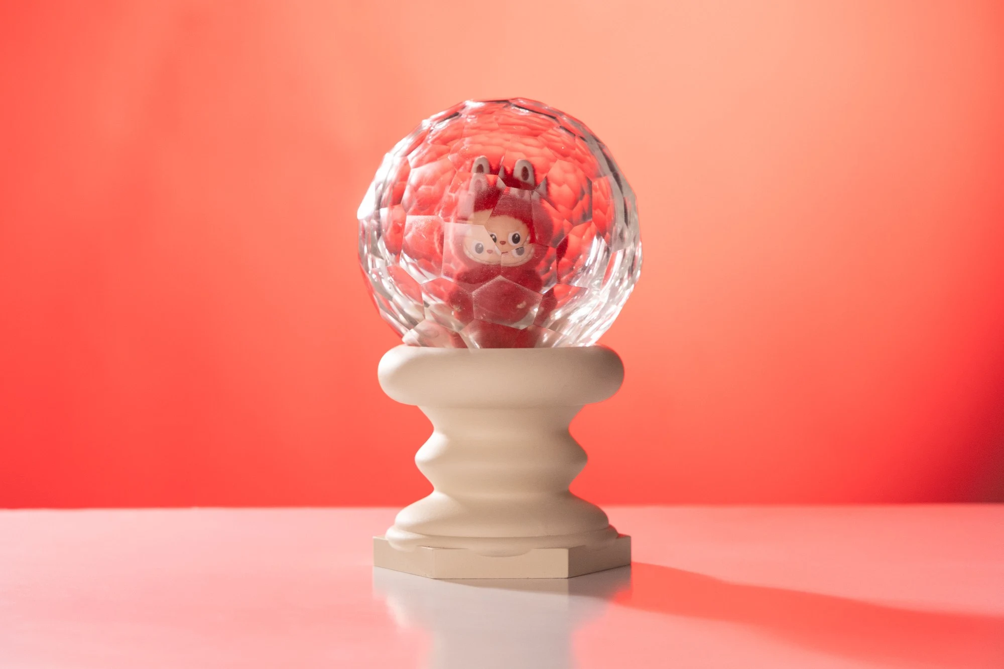 The piece against a coral red background